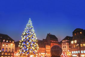 christmas market in Europe, decorated xmas tree on the street of city, woman in warm hat enjoying cozy atmosphere